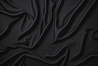 The primary subject of the image is a black fabric, which appears to be a piece of clothing or a curtain. The setting is a dark room, and the visual style is a close-up of the fabric. The colors and mood of the image are predominantly dark and moody, with the black fabric being the main focus.