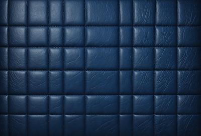 The primary subject of the image is a blue leather couch. The setting is a room with a blue wall, and the visual style is a close-up of the couch. The colors and mood of the image are predominantly blue, creating a calm and relaxing atmosphere.