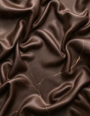 The primary subject of the image is a close-up of a brown fabric, possibly a piece of leather or a textured material. The setting is a room with a wall, and the visual style appears to be a photo. The colors in the image are predominantly brown, and the overall atmosphere is rich and textured.