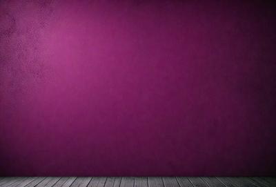 The primary subject of the image is a purple wall. The setting is a room with a wooden floor. The visual style is a photo, and the dominant colors are purple and pink. The overall atmosphere is calm and serene.