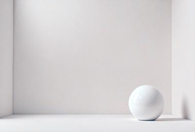 The primary subject of the image is a white sphere, which is placed on a white surface. The setting is a white wall, and the visual style appears to be a photo. The colors and mood of the image are predominantly white, creating a clean and minimalist atmosphere.