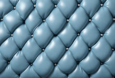 The primary subject of the image is a blue couch with a patterned design. The setting is a room with a blue background. The visual style is a close-up of the couch, showcasing its unique design. The colors and mood of the image are predominantly blue, creating a calm and relaxing atmosphere.