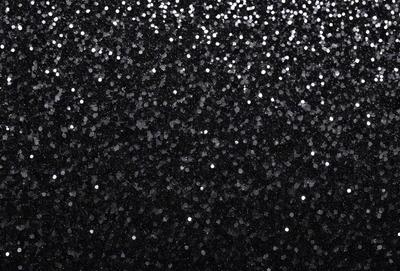 The primary subject of the image is a close-up of a black background with a pattern of white stars. The setting is a dark room, and the visual style is a black and white photo. The dominant colors are black and white, creating a moody and dramatic atmosphere.