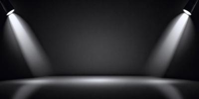 The primary subject of the image is a black background with a light source shining on it. The setting is a dark room, and the visual style is a black and white photo. The colors and mood of the image are predominantly dark and moody, with the light source creating a contrasting effect.