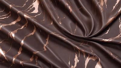 The primary subject of the image is a brown fabric with a pattern of brown and white. The setting is a close-up of the fabric, showcasing its intricate design. The visual style is a detailed, textured image that highlights the fabric's unique pattern. The colors and mood of the image are warm and earthy, with the brown and white pattern creating a sense of depth and texture.