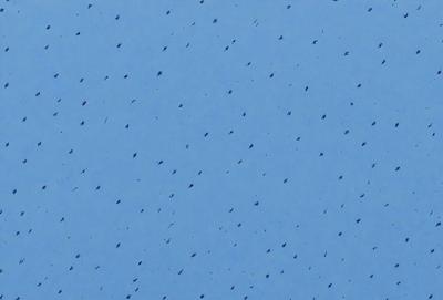 The primary subject of the image is a blue sky with a pattern of dots or holes. The setting is a clear blue sky, and the visual style appears to be a photo or a digital artwork. The colors and mood of the image are predominantly blue, creating a calm and serene atmosphere.
