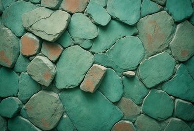 The primary subject of the image is a green stone wall with various shapes and sizes of green rocks. The setting is a rocky outdoor environment, and the visual style appears to be a photo of the stone wall. The dominant colors are green, and the overall atmosphere is natural and rugged.