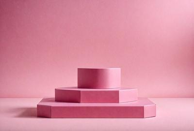 The primary subject of the image is a stack of three pink boxes. The setting is a pink background, which creates a visually appealing contrast with the boxes. The visual style is a photo, capturing the details and colors of the boxes. The colors and mood of the image are predominantly pink, giving it a warm and inviting atmosphere.