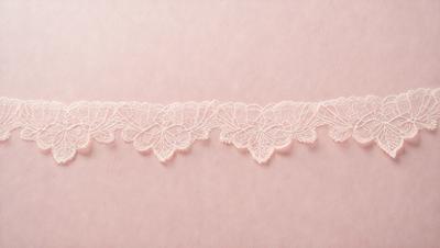 The primary subject of the image is a white lace trim. The setting is a pink background, which creates a contrast with the white lace. The visual style is a close-up of the lace trim, showcasing its intricate details. The colors and mood of the image are predominantly pink and white, giving it a delicate and elegant appearance.