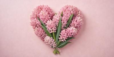 The primary subject of the image is a bouquet of pink flowers, which are arranged in the shape of a heart. The flowers are placed on a pink background, creating a visually appealing and romantic scene. The visual style of the image is a close-up of the flowers, showcasing their details and beauty. The colors and mood of the image are predominantly pink, which is often associated with love and affection.