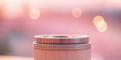 The primary subject of the image is a silver metal object, possibly a metal bowl or a metal container, placed on a pink surface. The setting appears to be a room with a pink background, and the visual style is a close-up of the metal object. The colors in the image are predominantly pink, creating a warm and inviting atmosphere.