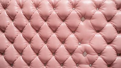 The primary subject of the image is a pink cushion with a pattern of pink and white squares. The setting is a room with a pink background, and the visual style is a close-up of the cushion. The colors and mood of the image are predominantly pink, creating a warm and inviting atmosphere.