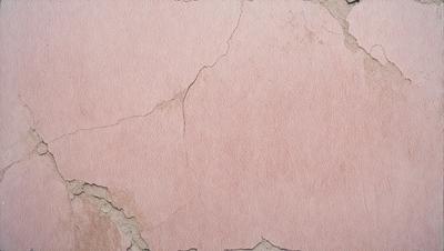 The primary subject of the image is a pink wall with a peeling paint surface. The setting is a room with a pink wall, and the visual style is a close-up of the wall. The colors and mood of the image are predominantly pink, giving it a warm and inviting atmosphere.