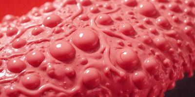 The primary subject of the image is a close-up of a pink surface with a lot of bubbles on it. The surface appears to be a wet, possibly pinkish, material. The setting is a room with a pink background, which adds to the overall atmosphere of the image. The visual style is a close-up of the pink surface with bubbles, creating a unique and interesting pattern. The colors and mood of the image are predominantly pink, giving it a warm and inviting feel