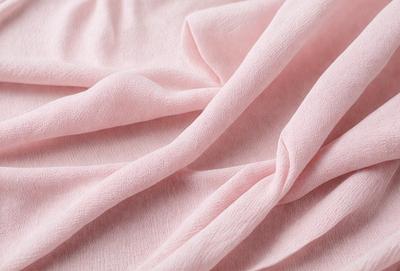 The primary subject of the image is a pink sheet or blanket. The setting is a bed, and the visual style is a close-up of the pink fabric. The colors and mood of the image are predominantly pink, creating a warm and cozy atmosphere.