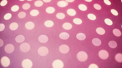 The primary subject of the image is a pattern of polka dots on a purple background. The setting is a close-up of the polka dots, showcasing their texture and pattern. The visual style is a combination of a photo and digital art, as the polka dots are displayed in a visually appealing manner. The colors and mood of the image are predominantly purple, creating a calm and soothing atmosphere.