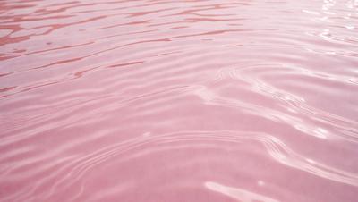 The primary subject of the image is a pink water surface, which appears to be a pink waterfall or a pink ocean. The setting is a pink water body, and the visual style is a close-up of the water surface. The colors and mood of the image are predominantly pink, creating a unique and visually striking scene.