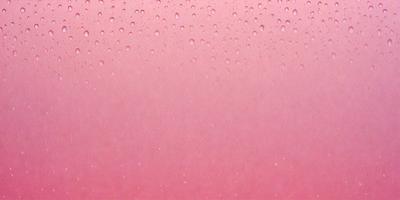 The primary subject of the image is a pink surface with water droplets on it. The setting is a pink background, and the visual style is a close-up of the pink surface. The colors and mood of the image are predominantly pink, creating a warm and inviting atmosphere.