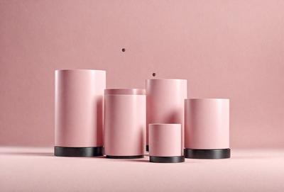 The primary subject of the image is a group of four pink vases. They are placed on a pink surface, which creates a cohesive and visually appealing scene. The vases are of varying sizes, with one being larger than the others. The visual style of the image is a close-up of the vases, showcasing their unique shapes and colors. The overall atmosphere of the image is warm and inviting, with the pink vases and surface creating a sense of harmony and elegance.