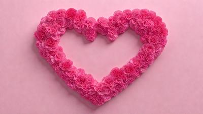 The primary subject of the image is a heart-shaped arrangement of pink flowers. The heart is made up of multiple layers of pink flowers, creating a visually appealing and romantic display. The setting is a pink background, which complements the heart and adds to the overall mood of the image. The visual style of the image is a combination of photo and digital art, resulting in a unique and artistic representation of the heart-shaped flower arrangement. The colors and mood of the image are predominantly