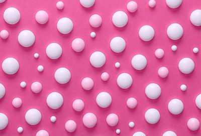 The primary subject of the image is a pattern of pink and white balls. The setting is a pink background, and the visual style appears to be a digital art or illustration. The dominant colors are pink and white, creating a warm and inviting atmosphere.