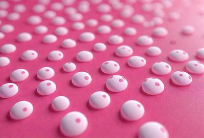 The primary subject of the image is a pink surface with numerous white circles or bumps on it. The setting appears to be a pink background, and the visual style is a close-up of the pink surface with the white circles. The dominant colors are pink and white, creating a soft and warm atmosphere.