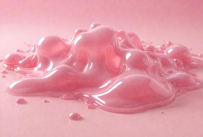 The primary subject of the image is a pink, gooey substance that appears to be a liquid or a gel. The setting is a pink background, which adds to the overall mood of the image. The visual style is a close-up of the pink substance, showcasing its texture and appearance. The colors and mood of the image are predominantly pink, creating a sense of warmth and softness.