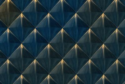 The primary subject of the image is a blue and yellow patterned wallpaper. The setting is a room with a blue and yellow wallpapered wall. The visual style is a patterned wallpaper, which gives the room a unique and vibrant atmosphere. The dominant colors are blue and yellow, creating a lively and energetic environment.