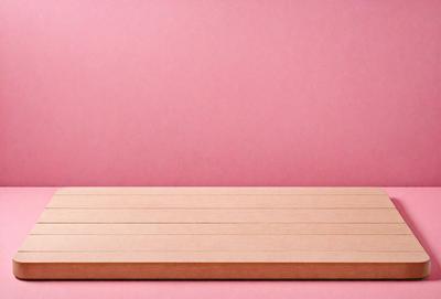 The primary subject of the image is a wooden board, which is placed on a pink surface. The setting is a room with a pink wall, and the visual style appears to be a photo. The dominant colors in the image are pink and brown, creating a warm and inviting atmosphere.
