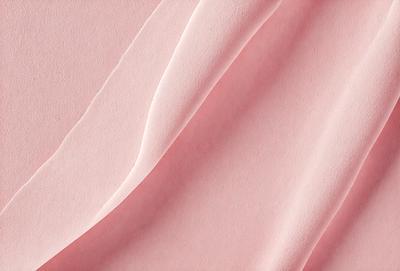 The primary subject of the image is a pink sheet of paper. The setting is a close-up of the paper, showcasing its texture and color. The visual style is a realistic representation of the paper, and the colors and mood are predominantly pink, creating a warm and inviting atmosphere.