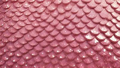 The primary subject of the image is a pink sequin fabric with a pattern of pink and white sequins. The setting is a close-up view of the sequin fabric, showcasing its intricate design. The visual style is a close-up of the sequin fabric, which gives a sense of texture and detail. The colors and mood of the image are predominantly pink and white, creating a soft and elegant atmosphere.