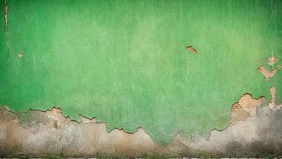 The primary subject of the image is a green wall with a hole in it. The setting is an outdoor environment, and the visual style appears to be a photo. The dominant colors are green and brown, creating a natural and earthy atmosphere.