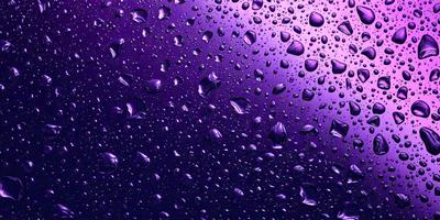 The primary subject of the image is a purple background with a lot of raindrops falling on it. The setting is a dark, purple-colored environment, which creates a moody atmosphere. The visual style is a close-up of the raindrops, showcasing the details of the water droplets. The colors and mood of the image are predominantly purple, with the raindrops adding a sense of movement and dynamism to the scene.