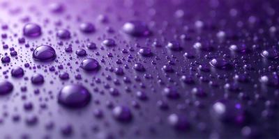 The primary subject of the image is a close-up of water droplets on a purple surface. The setting is a purple background, and the visual style appears to be a photo. The colors and mood of the image are predominantly purple, creating a calm and serene atmosphere.