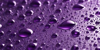 The primary subject of the image is a close-up of water droplets on a purple surface. The setting is a purple background, and the visual style appears to be a photo. The colors and mood of the image are predominantly purple, creating a calm and serene atmosphere.