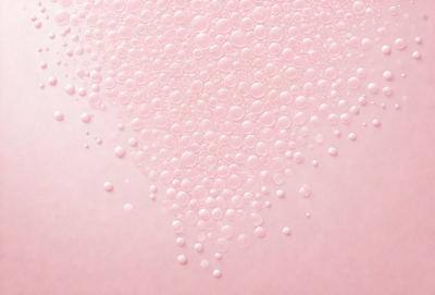 The primary subject of the image is a close-up of a pink surface with a pattern of bubbles. The setting is a white background, and the visual style appears to be a photo. The dominant colors are pink and white, creating a soft and delicate atmosphere.