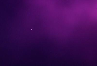 The image is a purple background with a small white dot in the center. The purple color creates a unique and artistic atmosphere. The white dot stands out against the purple background, drawing attention to it. The visual style of the image is a combination of a photo and a digital art, creating a striking and visually appealing scene.