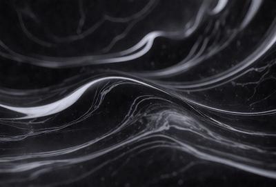 The primary subject of the image is a black and white photograph of a wave. The setting is a dark background, which contrasts with the wave's shape and texture. The visual style is a close-up of the wave, showcasing its intricate details. The colors and mood of the image are predominantly dark, with the wave's shape and texture being the main focus.