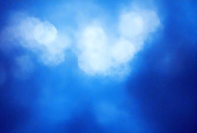The primary subject of the image is a cloudy blue sky. The setting is a clear day with a cloudy blue sky as the backdrop. The visual style is a natural, outdoor scene. The colors and mood are predominantly blue, creating a calm and serene atmosphere.