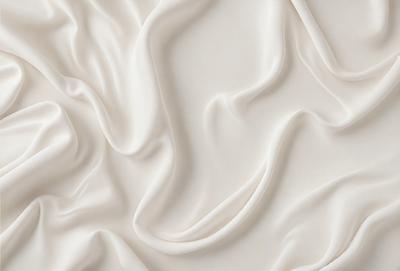 The primary subject of the image is a white sheet of fabric, which is the main object, scene, or focus of the image. The setting or background is a white surface, which provides a clean and minimalistic backdrop for the fabric. The visual style of the image is a close-up of the fabric, showcasing its texture and details. The colors and mood of the image are predominantly white, giving it a clean, serene, and calming atmosphere.