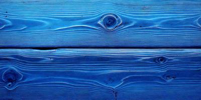 The primary subject of the image is a wooden plank with a blue surface. The setting is a wooden wall, and the visual style is a close-up of the wooden plank. The colors and mood of the image are predominantly blue, creating a calm and serene atmosphere.