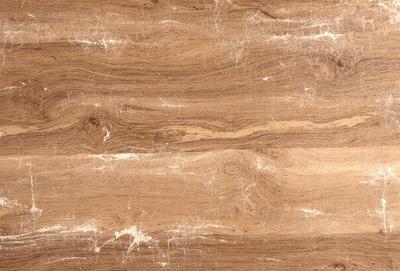 The primary subject of the image is a wooden surface, possibly a table or a piece of wood. The setting is a room with a wooden floor, and the visual style appears to be a close-up of the wooden surface. The colors and mood of the image are predominantly brown, giving it a warm and natural atmosphere.