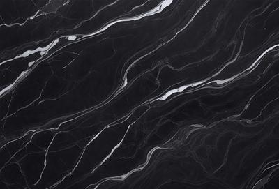 The primary subject of the image is a black marble countertop. The setting is a kitchen, with the countertop being the main focus of the scene. The visual style is a close-up of the marble countertop, showcasing its texture and pattern. The colors and mood of the image are predominantly dark, with the black marble countertop being the main source of contrast.