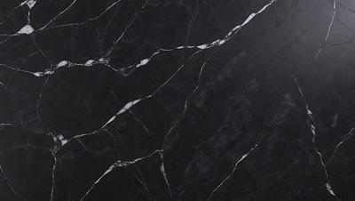 The primary subject of the image is a black marble countertop. The setting is a kitchen, with the countertop being the main focus of the scene. The visual style is a close-up of the marble countertop, showcasing its texture and details. The colors and mood of the image are predominantly dark, with the black marble countertop being the main source of contrast and visual interest.