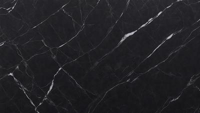 The primary subject of the image is a black marble countertop. The setting is a kitchen, with the countertop being the main focus of the scene. The visual style is a close-up of the marble countertop, showcasing its texture and pattern. The colors and mood of the image are predominantly dark, with the black marble countertop being the main source of contrast.