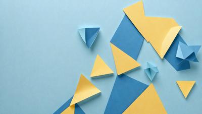 The primary subject of the image is a collection of yellow and blue triangles, which are arranged in various shapes and orientations. The setting is a blue surface, possibly a table or a wall. The visual style of the image is a combination of digital art and illustration, as the triangles are created using a pattern or a clipart. The dominant colors in the image are yellow and blue, giving it a vibrant and lively atmosphere.
