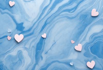 The primary subject of the image is a close-up of three pink hearts floating on a blue background. The hearts are arranged in a way that they appear to be floating on the surface of the water. The setting is a blue and white marbled surface, which adds a sense of depth and texture to the scene. The visual style of the image is a combination of photo and digital art, creating a unique and eye-catching design. The colors and mood of the image are predominantly pink and blue, evoking a
