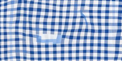 The primary subject of the image is a blue and white checkered pattern. The setting is a white surface, possibly a wall or a piece of fabric. The visual style is a close-up of the checkered pattern, which gives a sense of depth and texture to the image. The dominant colors are blue and white, creating a calm and soothing atmosphere.