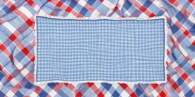 The primary subject of the image is a blue and white checkered cloth. The setting is a table with a red and white checkered cloth underneath the blue and white one. The visual style is a close-up of the blue and white checkered cloth. The colors and mood of the image are predominantly blue and white, creating a clean and classic atmosphere.