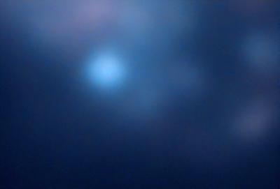 The primary subject of the image is a blue sky with a few white clouds. The setting is a dark, cloudy night, creating a moody atmosphere. The visual style is a photo, capturing the beauty of the night sky. The colors are predominantly blue and white, with the dark sky adding a sense of depth and contrast to the scene.